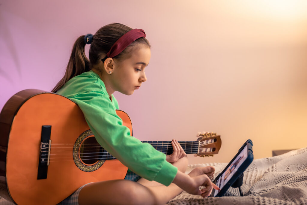 Dziewczynka ucząca się grać na gitarze z tabletu